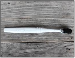 a tooth brush on a table with Activated Charcoal on the brush